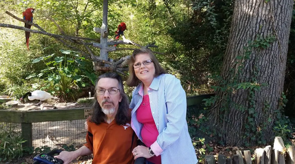 Two parrots in the background of me and my wife at the zoo